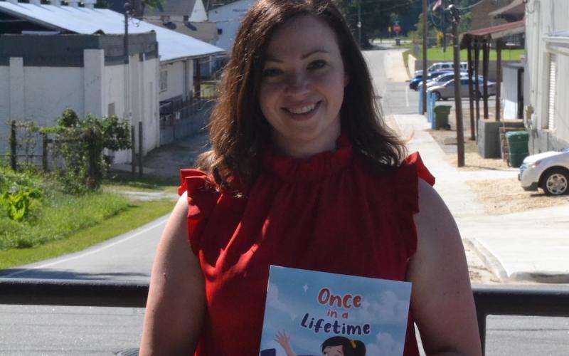 Emily Thompson holds a copy of "Once in a Lifetime," a children's book she authored in memory of her late best friend, Stevie Bruce.