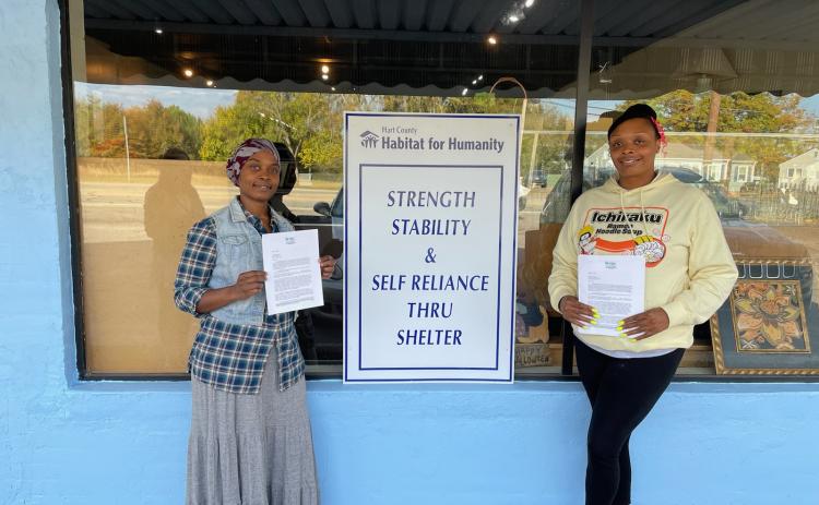 Hartwell residents Rebecca Durrett, left, and Brittany Harland, right, pose with their initial partner family agreement certificate with Hart County Habitat for Humanity building. Durrett and Harland were selected among several applicants for the newest home builds. 