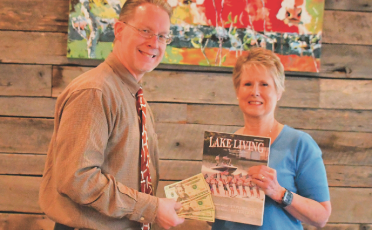 Enoch Autry, publisher for The Clayton Tribune in Rabun County, presents the $100 prize to Rabun County resident Melissa Elzey for winning the Spring 2023 Lake Living cover contest with her capture of the Lake Burton Ski Patriots’ performance on July 4, 2021.
